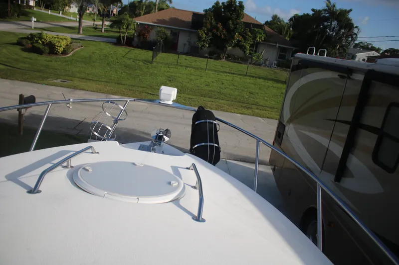 Slide: The Image of Bow view of 2011 Larson Carbiro 240 boat parked near an RV in a residential area. - 23