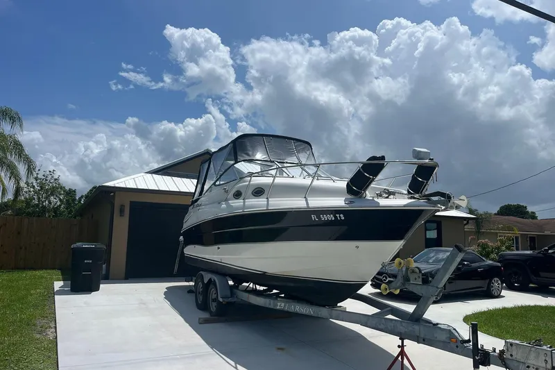 Slide: The Image of 2011 Larson Cabrio 240 boat on trailer in driveway under cloudy sky. - 3