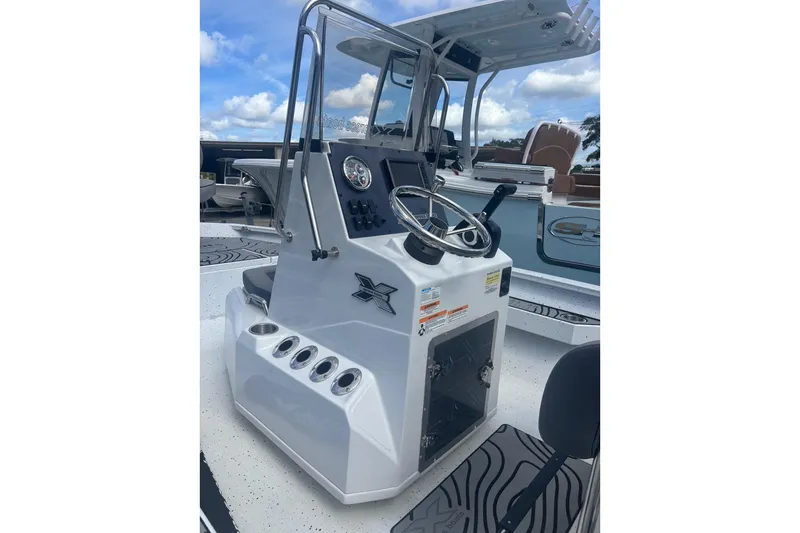 Slide: The Image of 2024 Xpress H20B Bay boat console with steering wheel and controls, under a blue sky. - 4