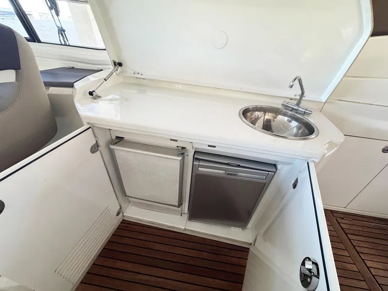 Slide: The Image of 2015 Beneteau Gran Turismo 44 yacht kitchenette with sink, mini fridge, and wooden flooring. - 15