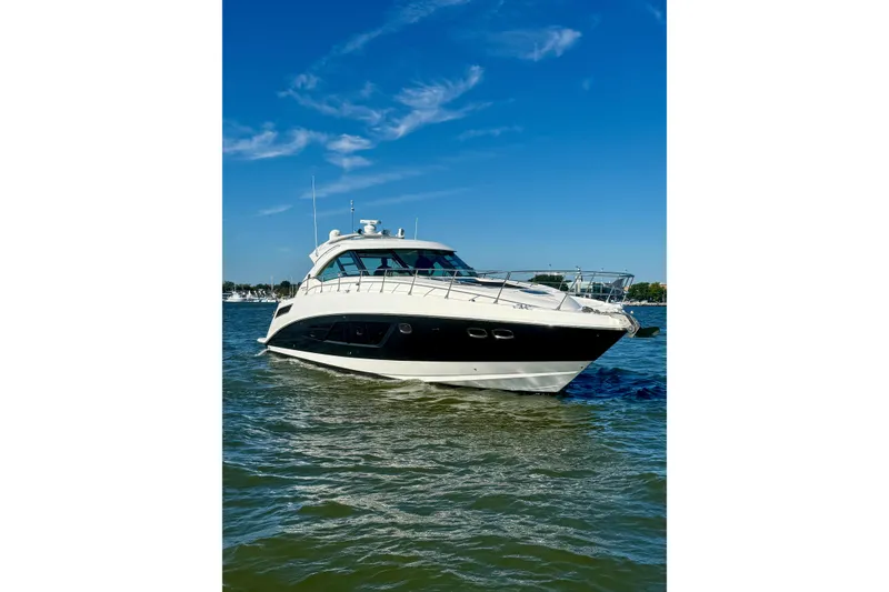 Slide: The Image of 2013 Sea Ray 540 Sundancer cruising under a large bridge on a cloudy day. - 2