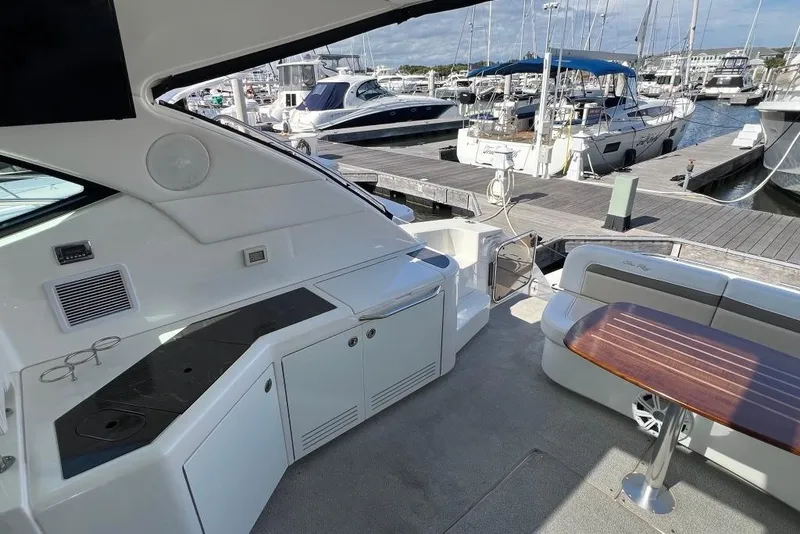 Slide: The Image of 2013 Sea Ray 540 Sundancer yacht cruising under a large bridge at sunset. - 8