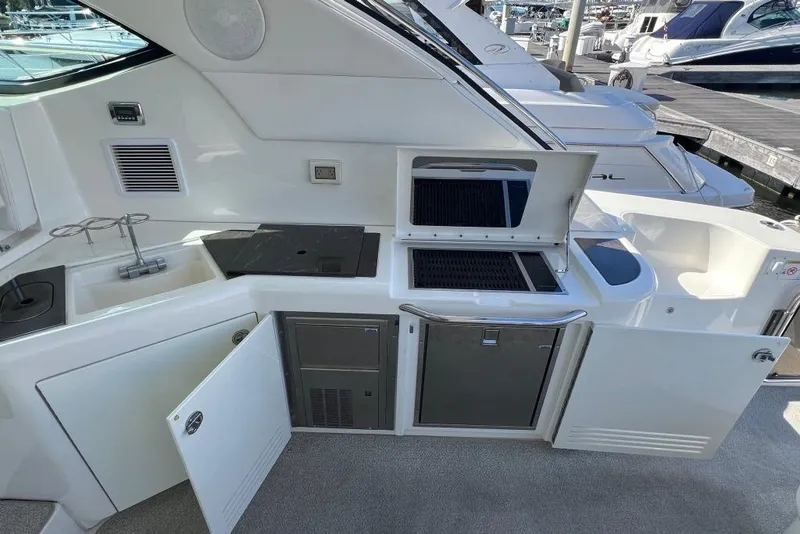 Slide: The Image of 2013 Sea Ray 540 Sundancer cruising under a large bridge at sunset. - 9