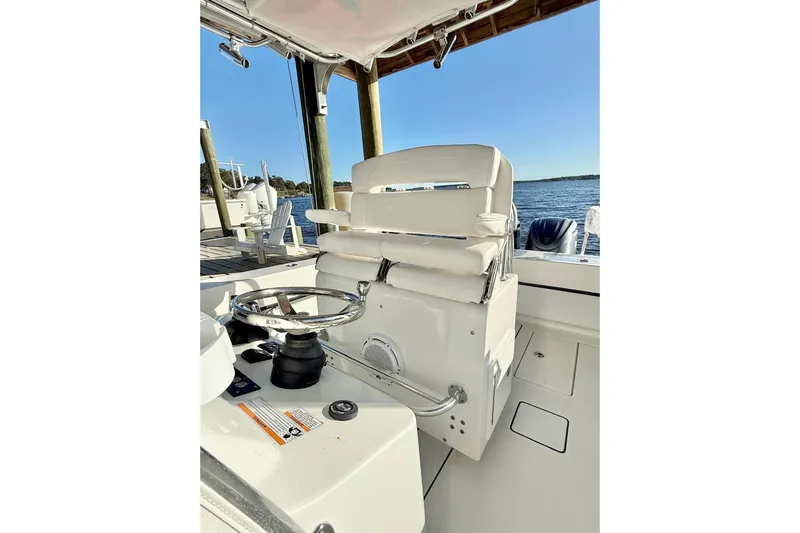 Slide: The Image of 2023 Contender 30 Tournament boat interior with steering wheel and seating, docked by the water. - 13