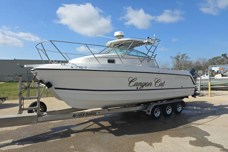 Slide: The Image of 2000 Glacier Bay 2670 Isle Runner boat on trailer, named "Canyon Cat," under clear blue sky. - 18