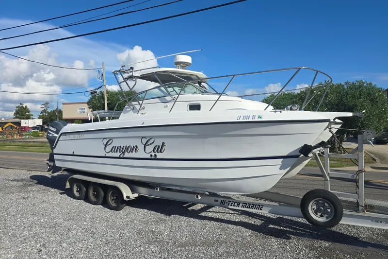 Slide: The Image of 2000 Glacier Bay 2670 Island Runner boat on trailer, named "Canyon Cat," parked roadside. - 6