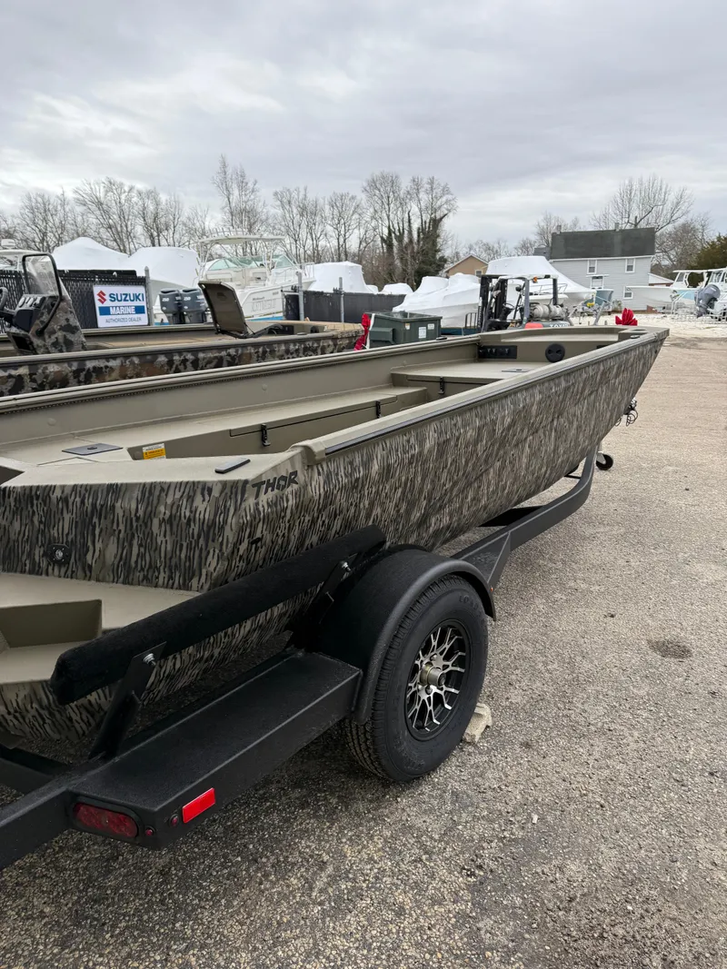 Slide: The Image of 2025 Thor 1754 Lake Hammer boat on trailer, camo design, parked outdoors. - 3