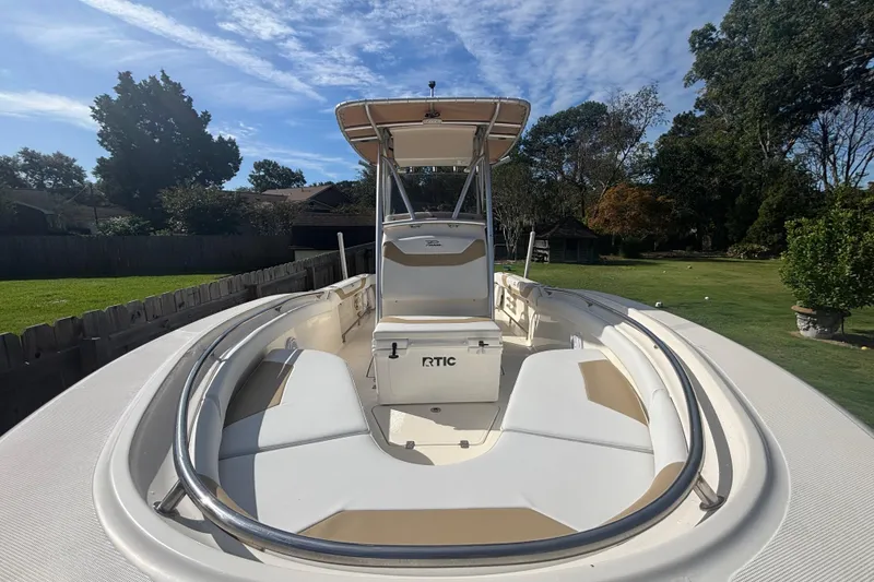 Slide: The Image of 2015 Pioneer 222 Sportfish boat with seating, parked in a grassy yard under a blue sky. - 7