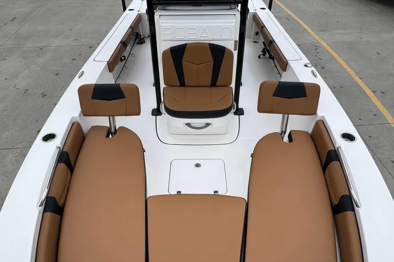 Slide: The Image of 2024 Robalo 226 Cayman boat interior with tan and black seating, docked on concrete. - 10
