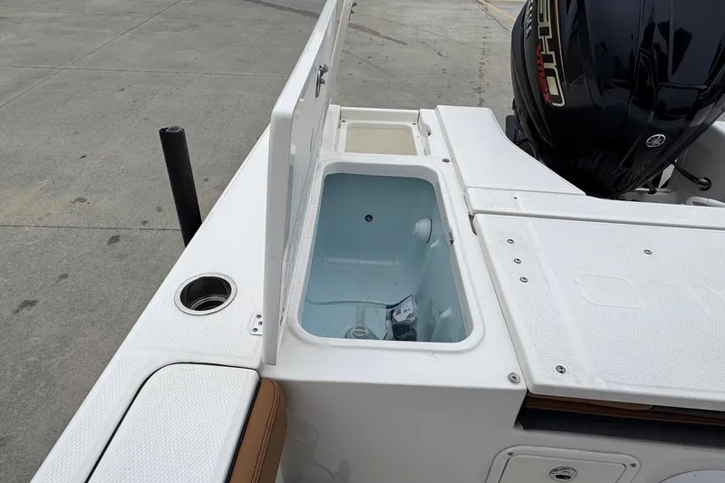 Slide: The Image of 2024 Robalo 226 Cayman boat with open storage compartment and Yamaha engine. - 19