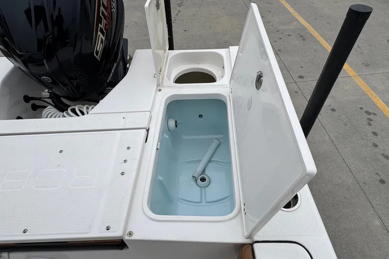 Slide: The Image of 2024 Robalo 226 Cayman boat with open storage compartment and visible engine. - 20