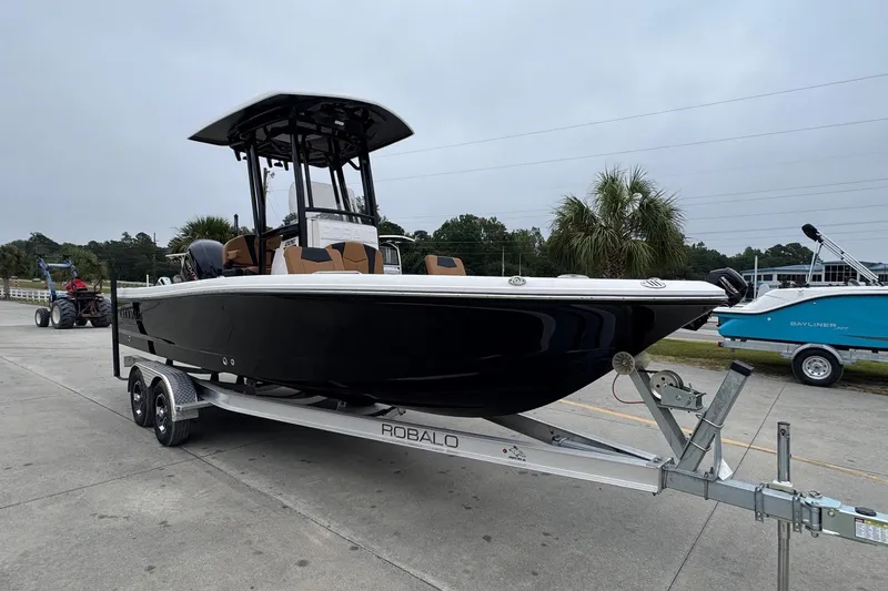 Slide: The Image of 2024 Robalo 226 Cayman boat on trailer, black hull, parked outdoors. - 4