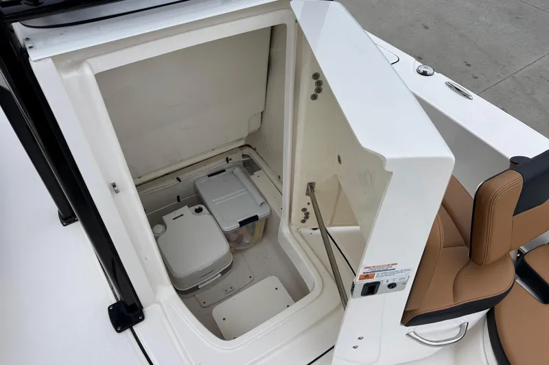 Slide: The Image of 2024 Robalo 226 Cayman boat storage compartment with portable toilet and seating. - 8
