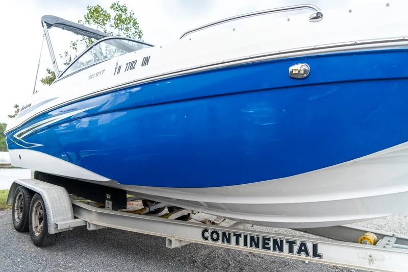 Slide: The Image of 2024 Hurricane SunDeck 217 OB boat on trailer, featuring a sleek blue and white design. - 5