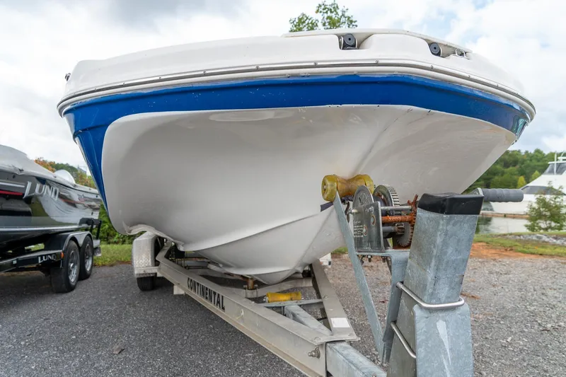 Slide: The Image of 2024 Hurricane SunDeck 217 OB boat on trailer, showcasing hull design and trailer mechanism. - 8