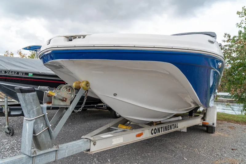 Slide: The Image of 2024 Hurricane SunDeck 217 OB boat on trailer, blue and white hull, parked outdoors. - 9
