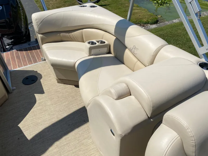 Slide: The Image of Luxurious seating on 2015 Misty Harbor 2685SU Tri Toon boat, featuring beige upholstery and cup holders. - 16