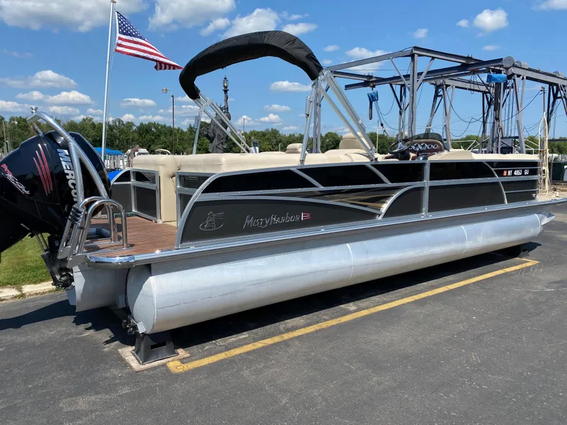 Slide: The Image of 2015 Misty Harbor 2685SU Tri Toon pontoon boat on trailer, sunny day, American flag. - 2