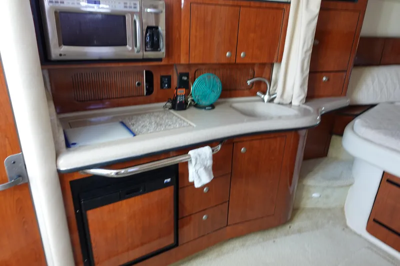 Slide: The Image of 2007 Sea Ray 320 Sundancer interior with kitchenette, featuring wood cabinets and modern appliances. - 17