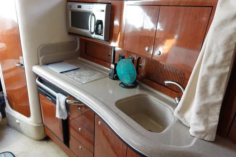 Slide: The Image of 2007 Sea Ray 320 Sundancer kitchen with microwave, sink, and wooden cabinetry. - 18