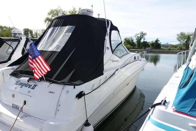 Slide: The Image of 2007 Sea Ray 320 Sundancer docked with American flag, featuring sleek design and black canopy. - 4