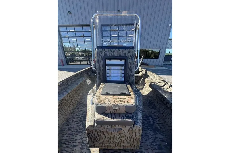 Slide: The Image of 2026 Xpress H20B Bay boat with camouflage seating, parked outside a building. - 22