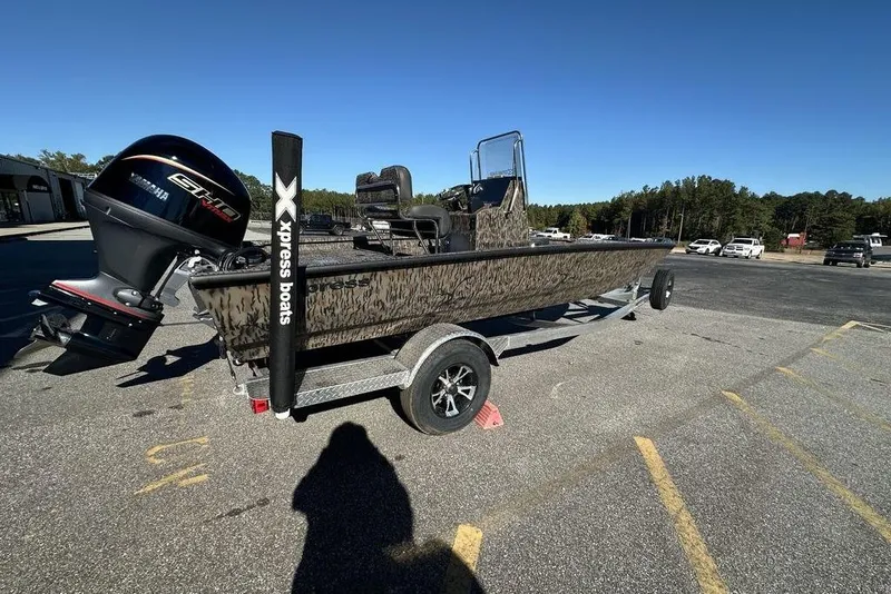 Slide: The Image of 2026 Xpress H20B Bay boat on trailer with outboard motor in parking lot. - 26