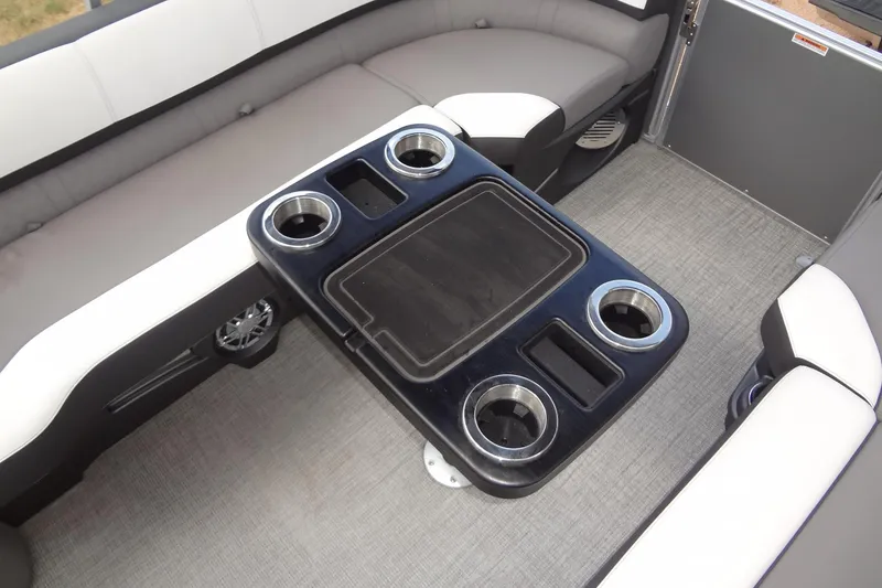 Slide: The Image of 2024 Tahoe Pontoon 2585 VRL interior with seating and cup holders on a sleek table. - 17