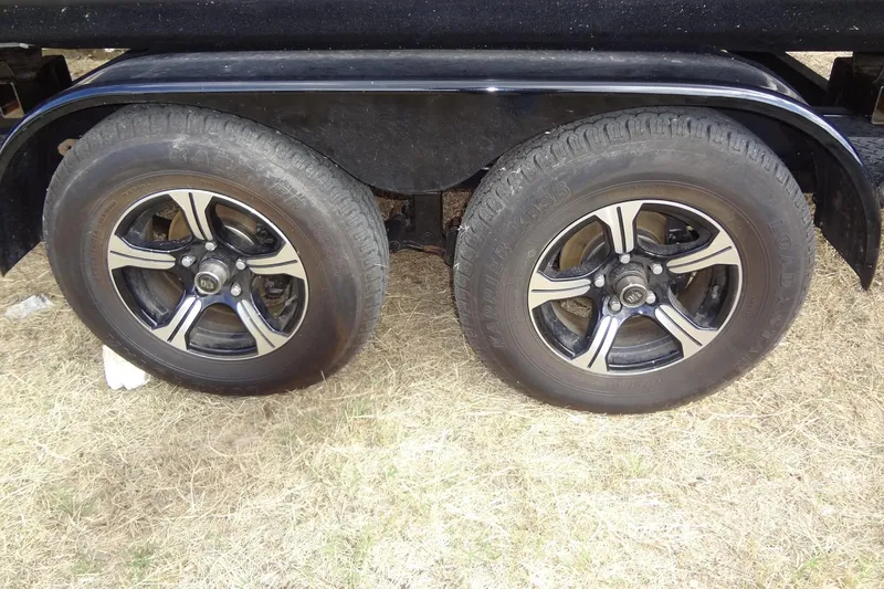 Slide: The Image of Trailer wheels of a 2024 Tahoe Pontoon 2585 VRL on grassy ground. - 41