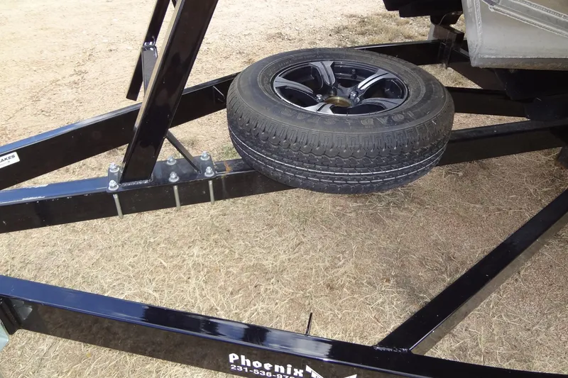 Slide: The Image of 2024 Tahoe Pontoon 2585 VRL trailer with spare tire on dry grass. - 42