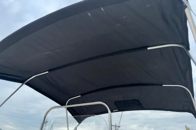 Slide: The Image of Bimini top of 2011 NauticStar 210 Coastal boat against cloudy sky. - 10