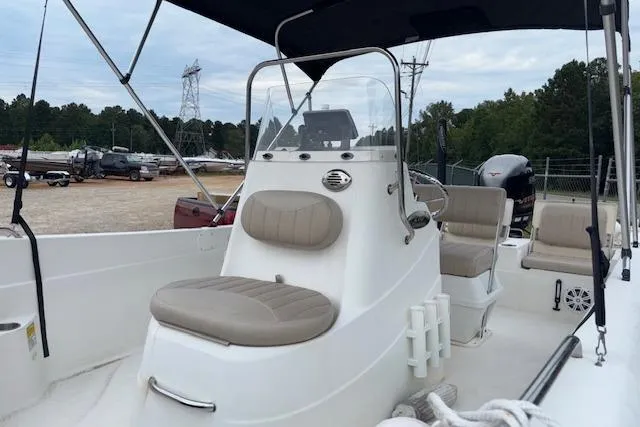 Slide: The Image of 2011 NauticStar 210 Coastal boat with beige seating and console, parked outdoors. - 6
