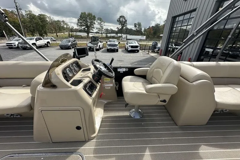 Slide: The Image of 2018 Manitou 23 Aurora LE RF boat interior with beige seating and control panel. - 10