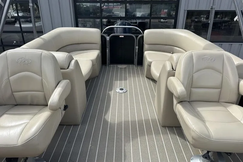 Slide: The Image of 2018 Manitou 23 Aurora LE RF boat interior with beige seating and striped flooring. - 12