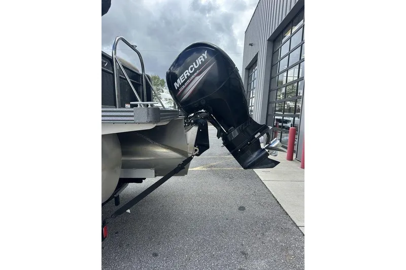 Slide: The Image of 2018 Manitou 23 Aurora LE RF with Mercury outboard motor in a parking lot. - 2