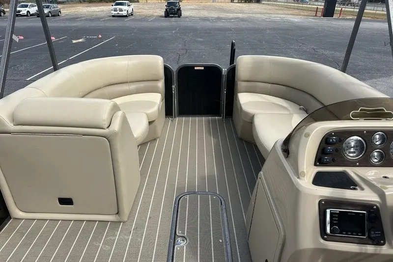 Slide: The Image of 2018 Manitou 23 Aurora LE RF pontoon boat interior with beige seating and control panel. - 7
