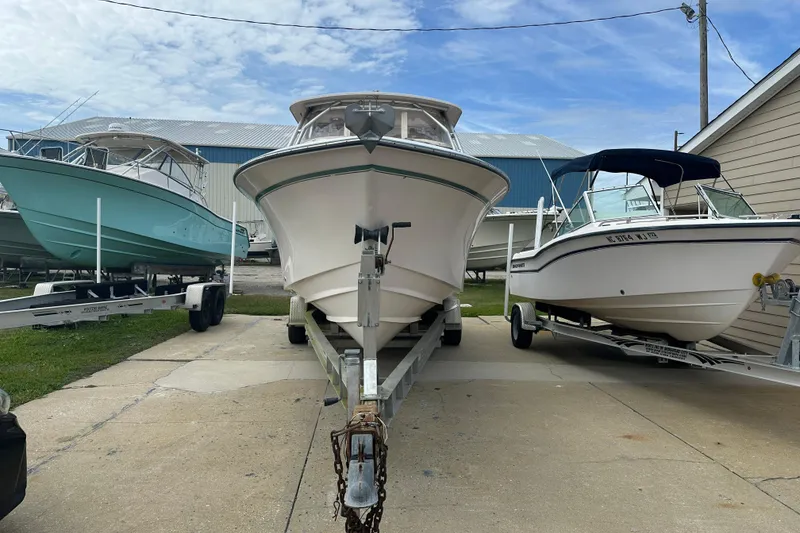 Slide: The Image of 2012 Grady-White Freedom 275 boat on trailer, flanked by other boats, under blue sky. - 2