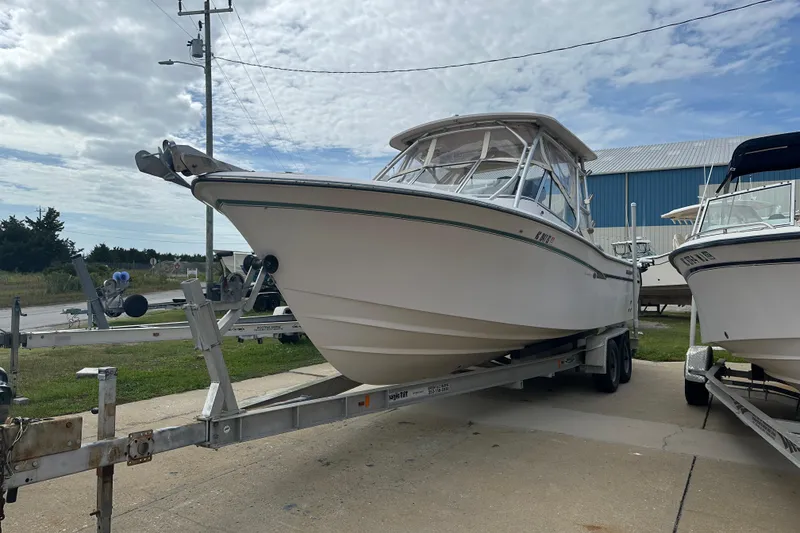 Slide: The Image of 2012 Grady-White Freedom 275 boat on trailer, parked outdoors under cloudy sky. - 3