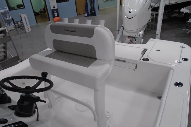 Slide: The Image of 2026 Caymas 24 HB boat interior with steering wheel and seating in showroom. - 19