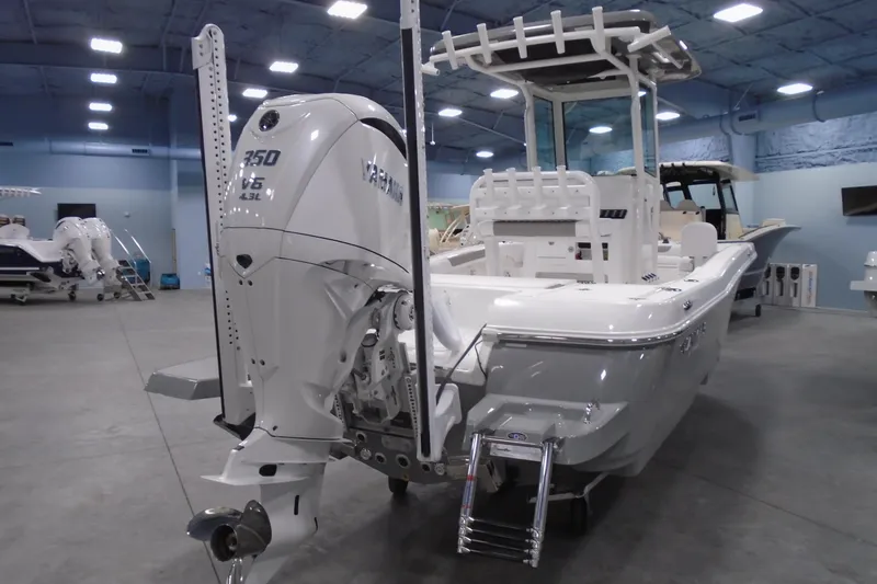 Slide: The Image of 2026 Caymas 24 HB boat with powerful outboard motor in showroom setting. - 3