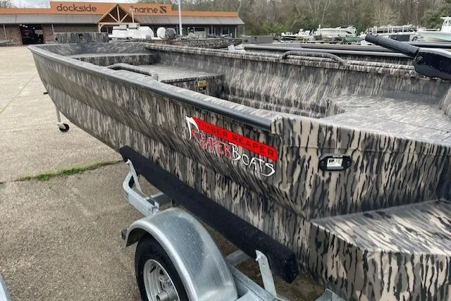 Slide: The Image of 2026 Reaper Boats 653-1690 model with camouflage design on a trailer at a marina. - 10