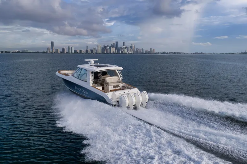 Slide: The Image of 2020 Boston Whaler 380 Realm cruising on open water with city skyline backdrop. - 6