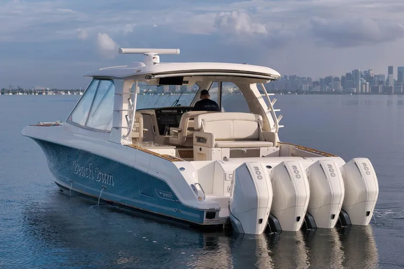 Slide: The Image of 2020 Boston Whaler 380 Realm boat with four engines on calm water, city skyline in background. - 9