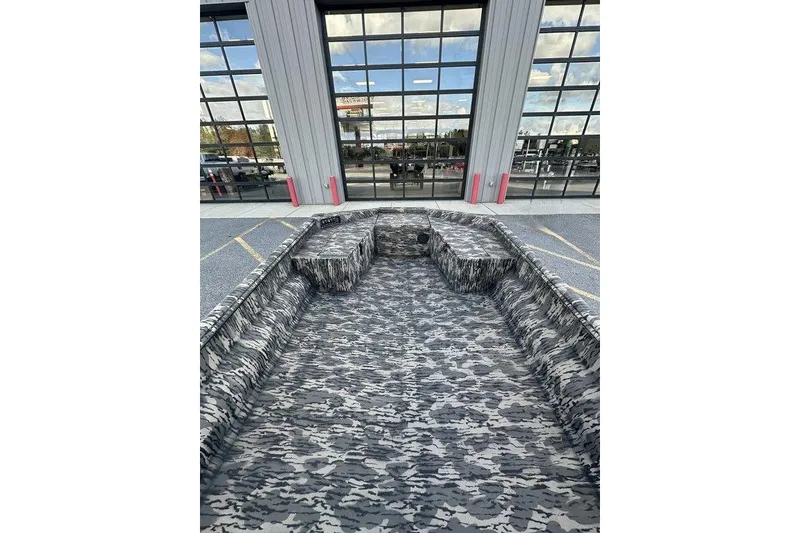 Slide: The Image of 2025 Havoc 1860 boat with camouflage interior, parked outside a building with glass windows. - 7