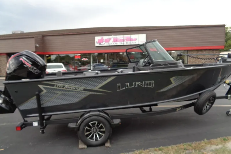 The Image of 2026 Lund 1775 Adventure Sport boat on trailer, parked outside a store. - 0