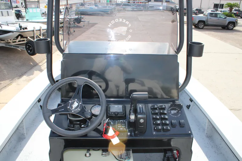 Slide: The Image of 2026 Freedom Boats 23' Warrior with Suzuki engine on trailer, outdoor dealership setting. - 16