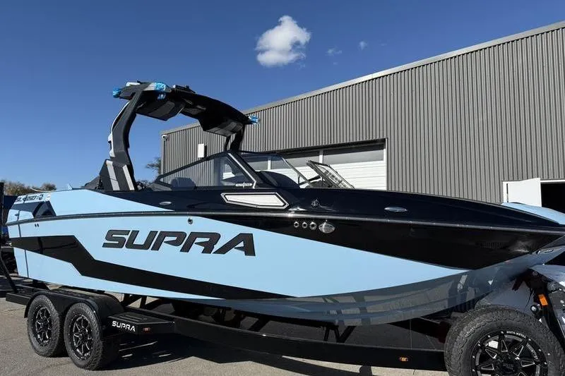 Slide: The Image of 2025 Supra SL 575 boat on trailer, sleek design, blue and black color scheme. - 3