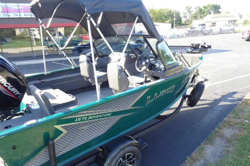 Slide: The Image of 2026 Lund 1675 Adventure Sport boat with canopy, parked on pavement. - 10