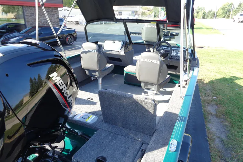 Slide: The Image of 2026 Lund 1675 Adventure Sport boat interior with Mercury engine, featuring seating and steering console. - 11