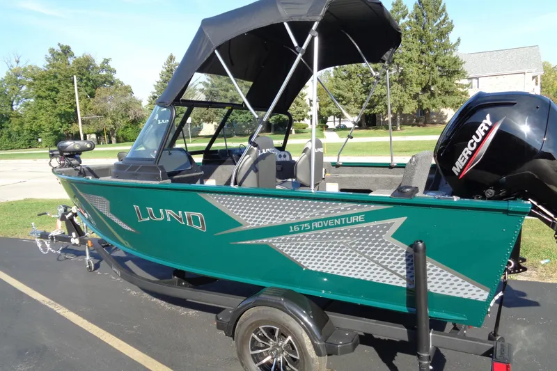 Slide: The Image of 2026 Lund 1675 Adventure Sport boat with Mercury engine on trailer, parked outdoors. - 18